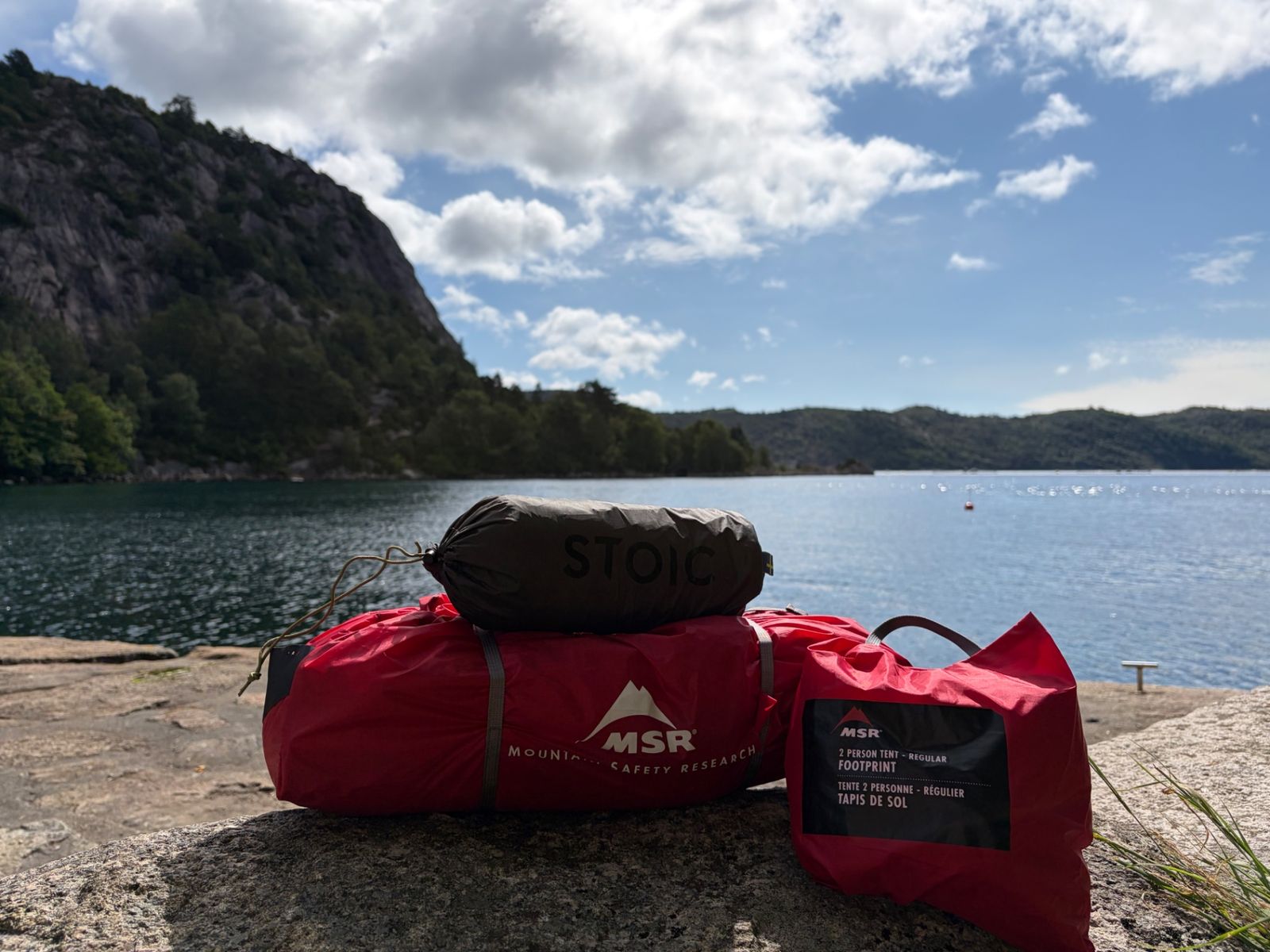 MSR Hubba Hubba NX tent with footprint and the Stoic tarp in their stuff sacks on a rock by the fjord